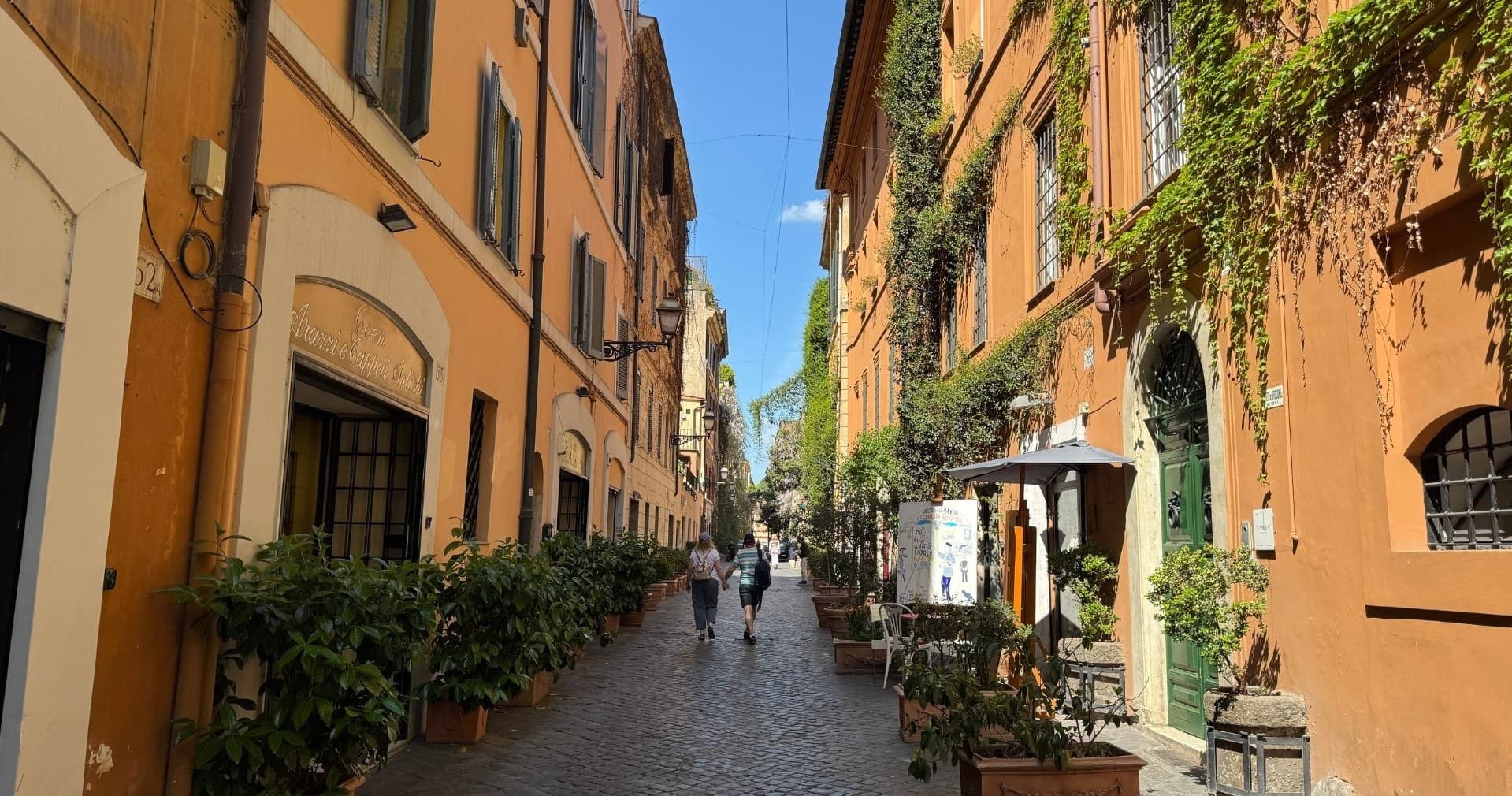 Italian cobblestone street with outdoor cafes and greenery