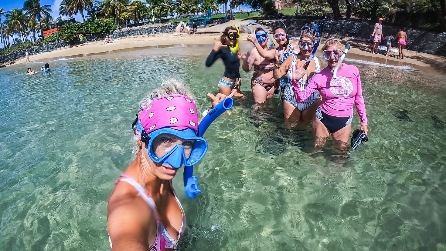 Guided beach walk with snorkelers heading toward reef