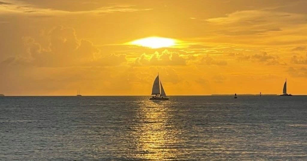 Sailboat at golden sunset on open ocean horizon