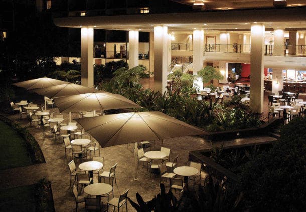Hotel outdoor dining terrace with umbrella tables at night
