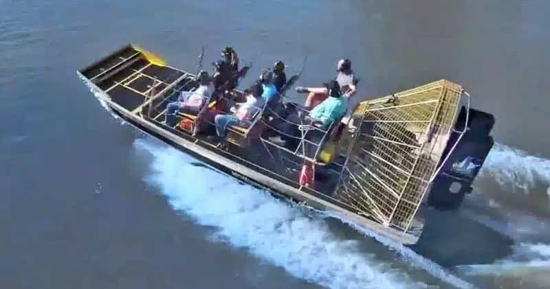Airboat tour with passengers speeding across marsh waters