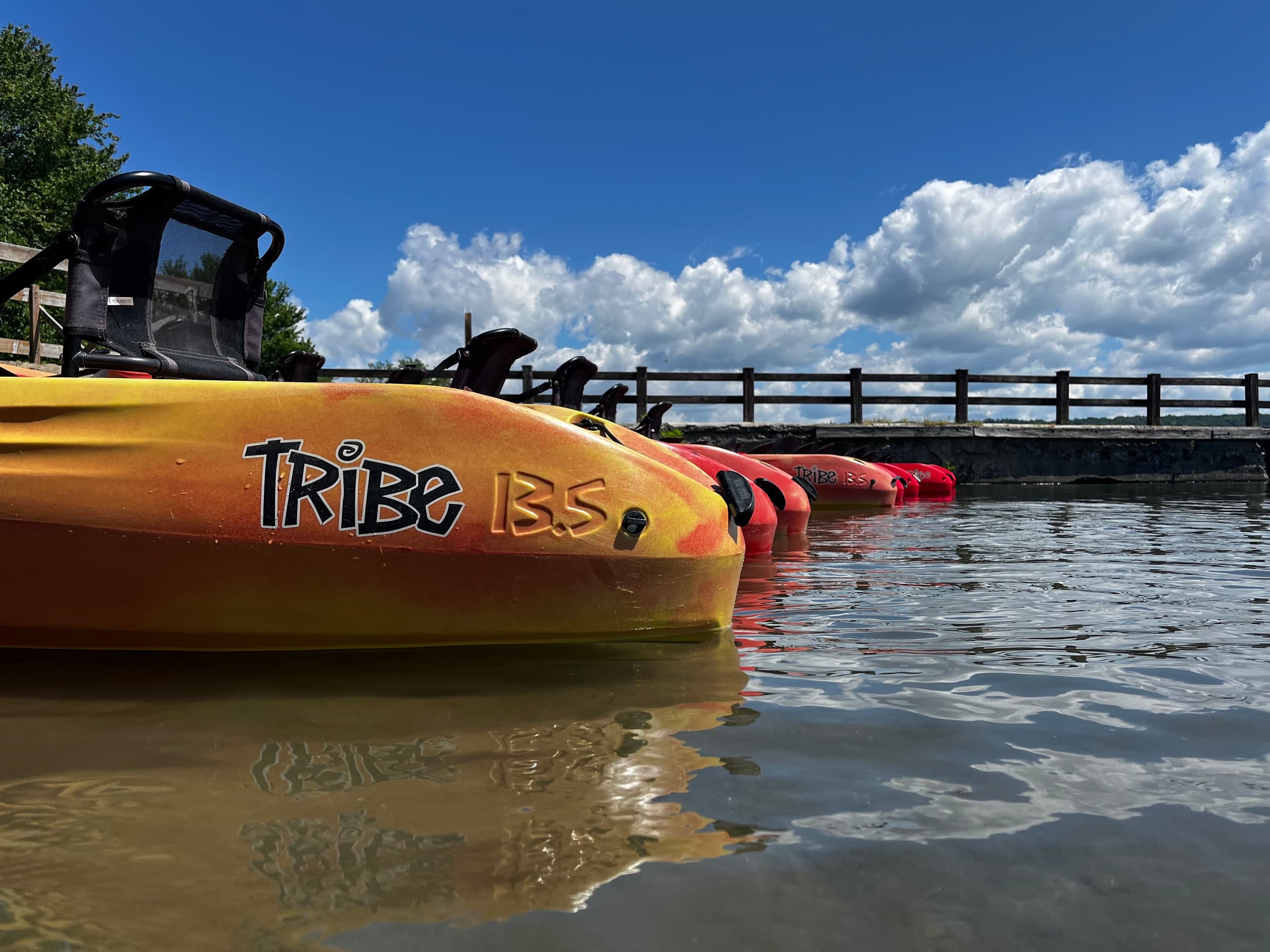 Bright kayaks stacked at dock with blue sky and clouds