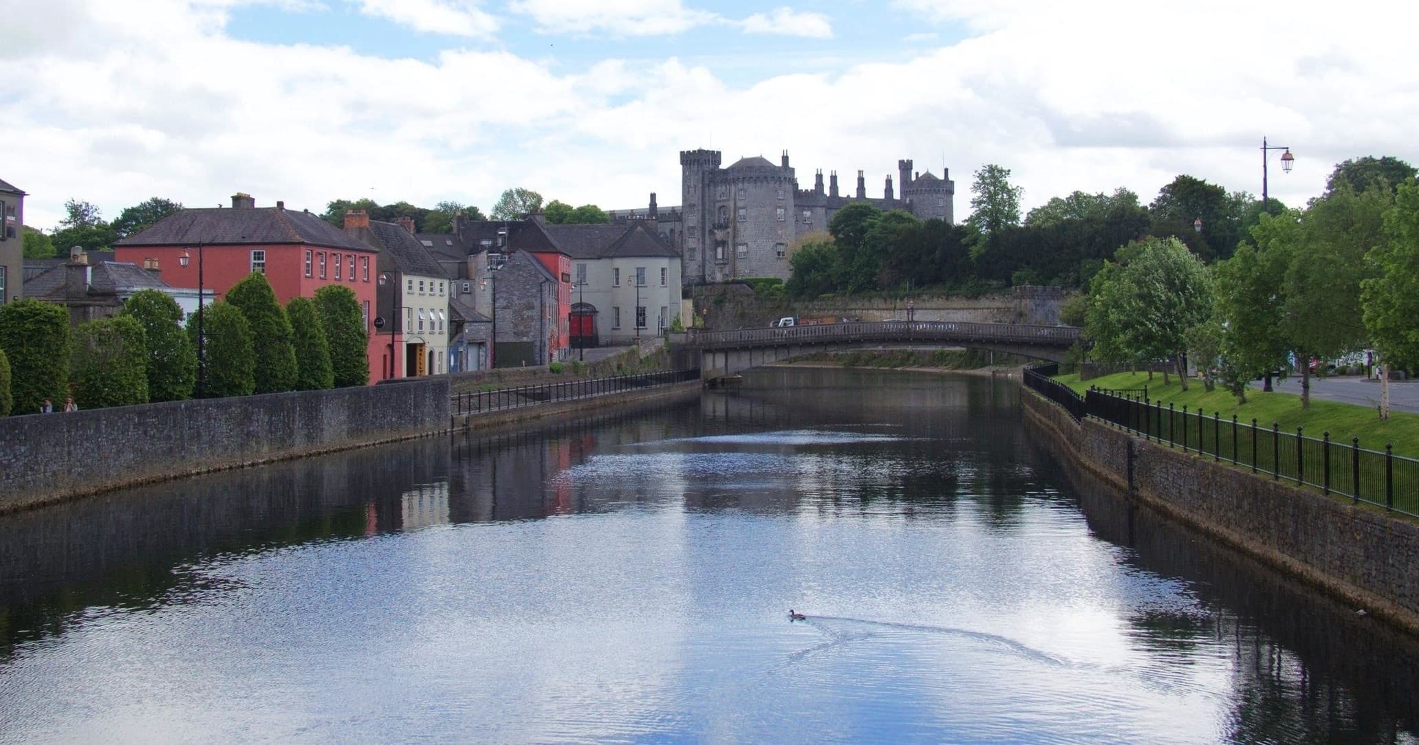 Scenic riverside walk by medieval castle in Ireland