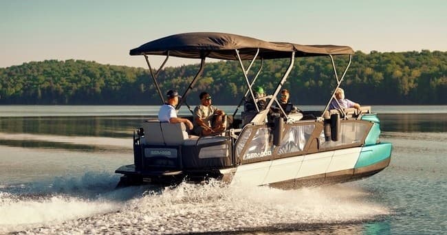 Pontoon boat cruising calm lake at sunrise with forest shore