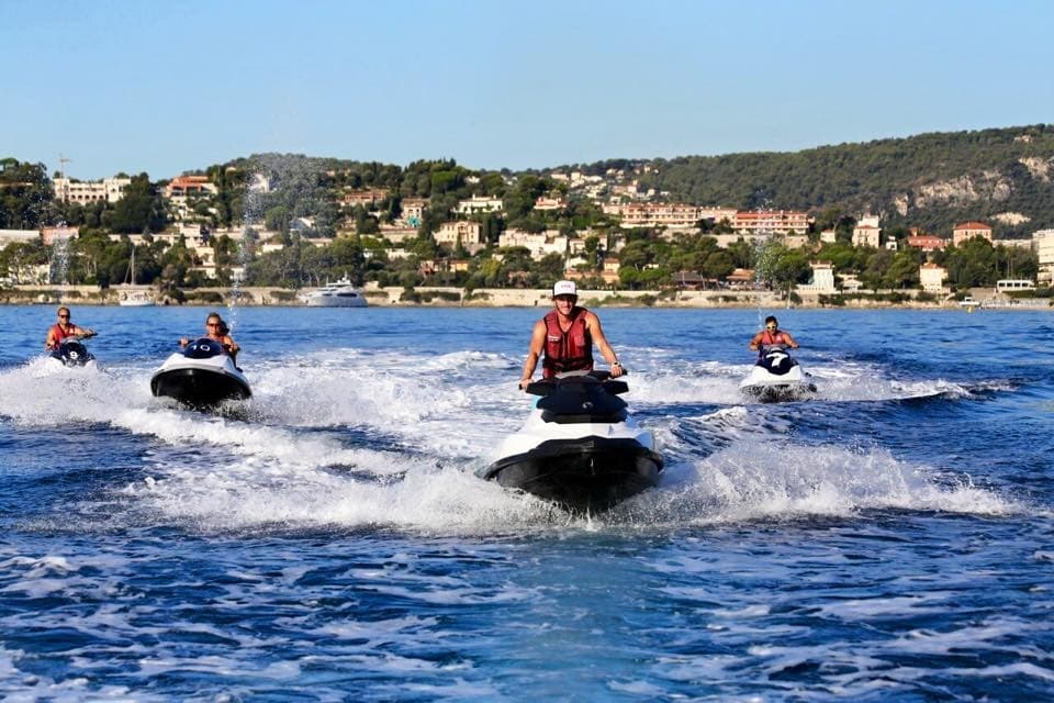 Three jet skis speeding across coastal waters near shoreline town