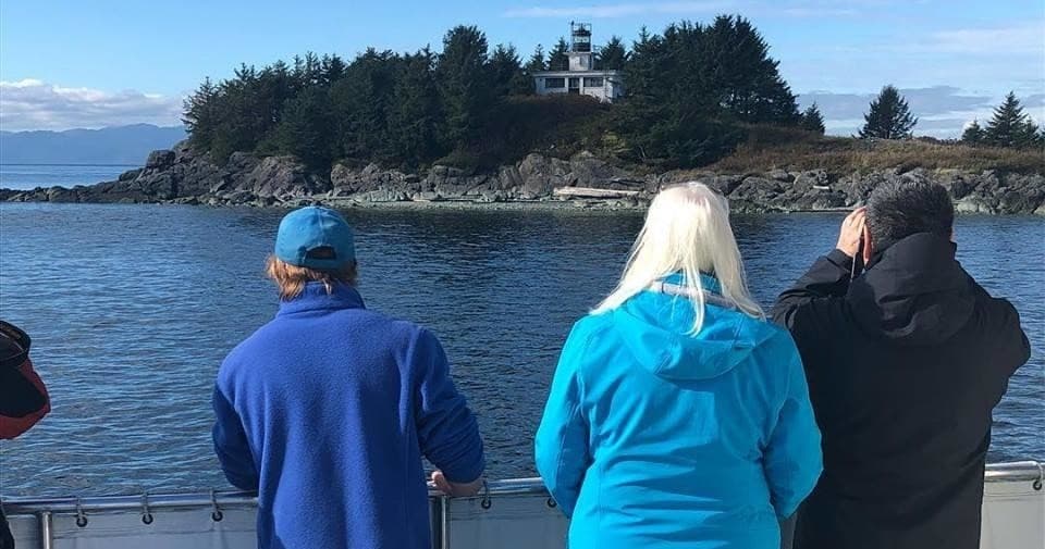 Passengers viewing forested island from whale-watching boat