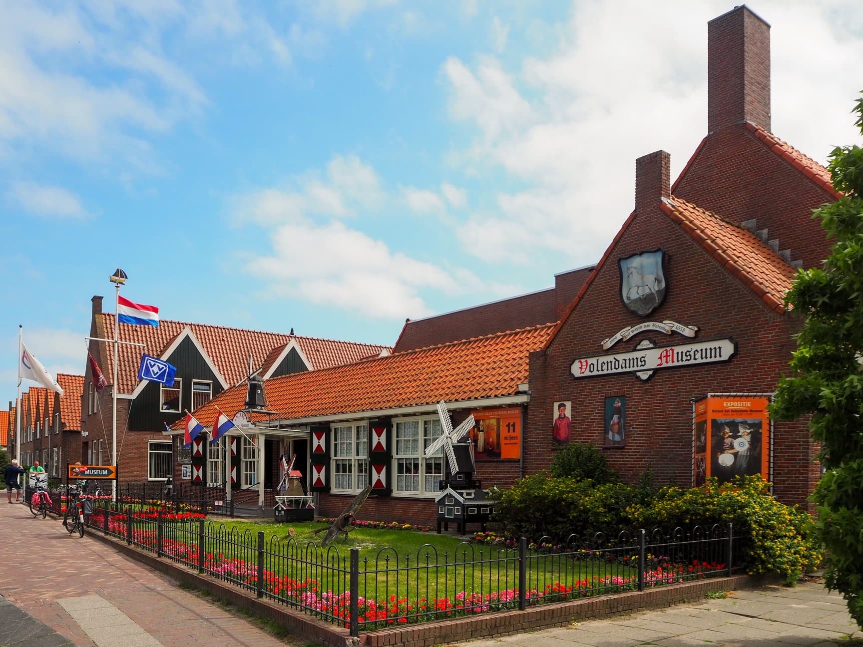 Volendams Museum exterior on sunny street with garden and flags