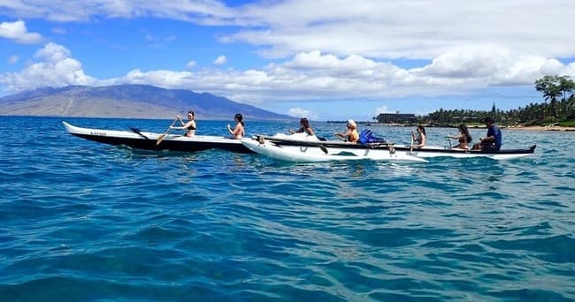 Group outrigger canoe team paddling along Maui coastline