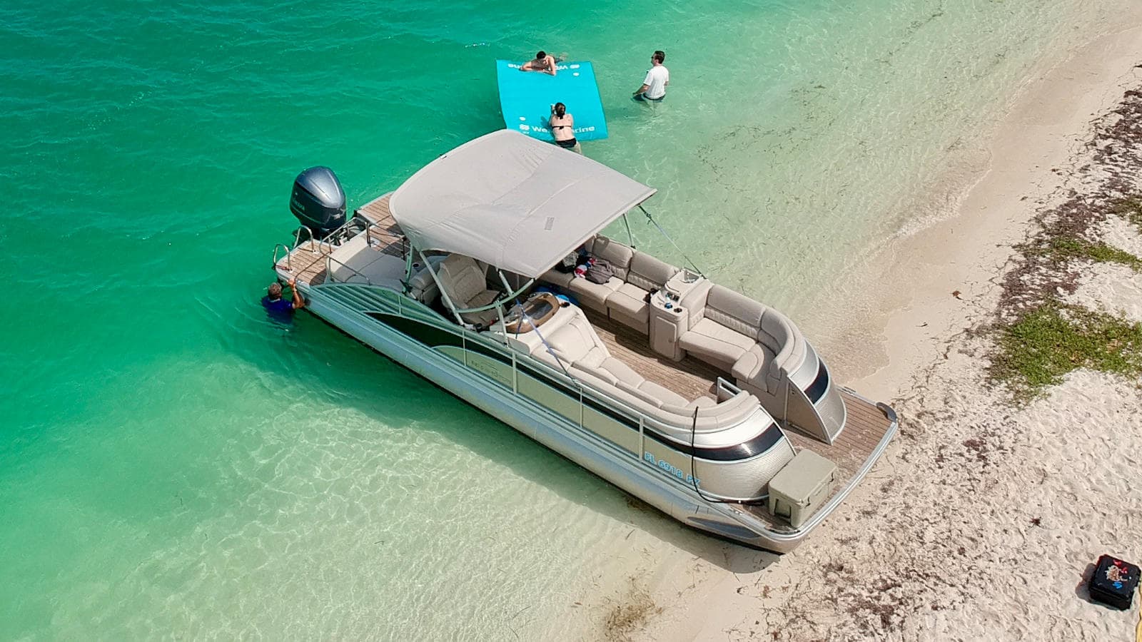 Aerial pontoon anchored on sandbar in turquoise shallow water