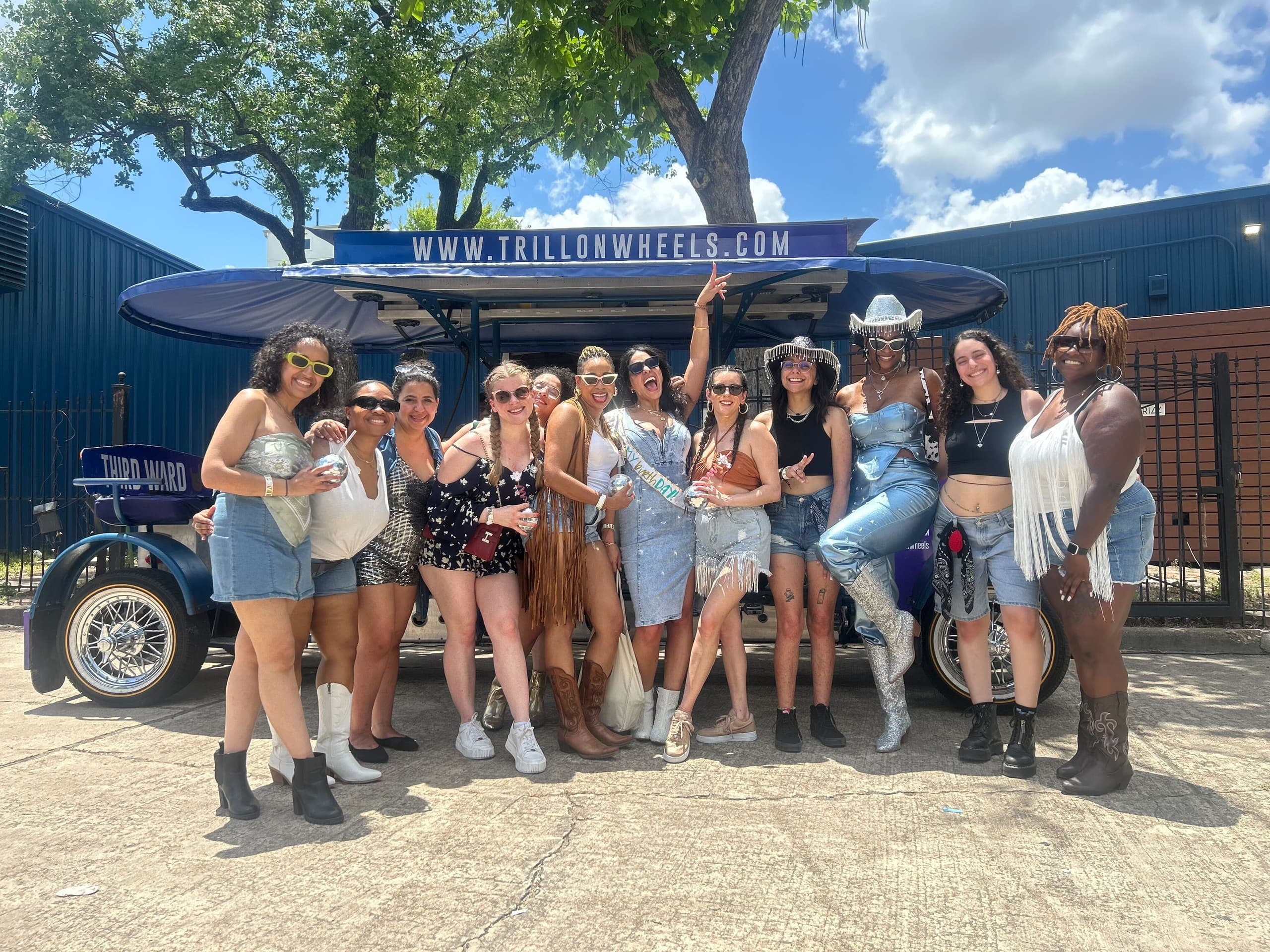 Group of riders posing by TrillonWheels party tram outdoors