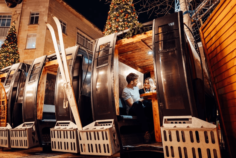 Couple dining inside festive outdoor market pod at Christmas market