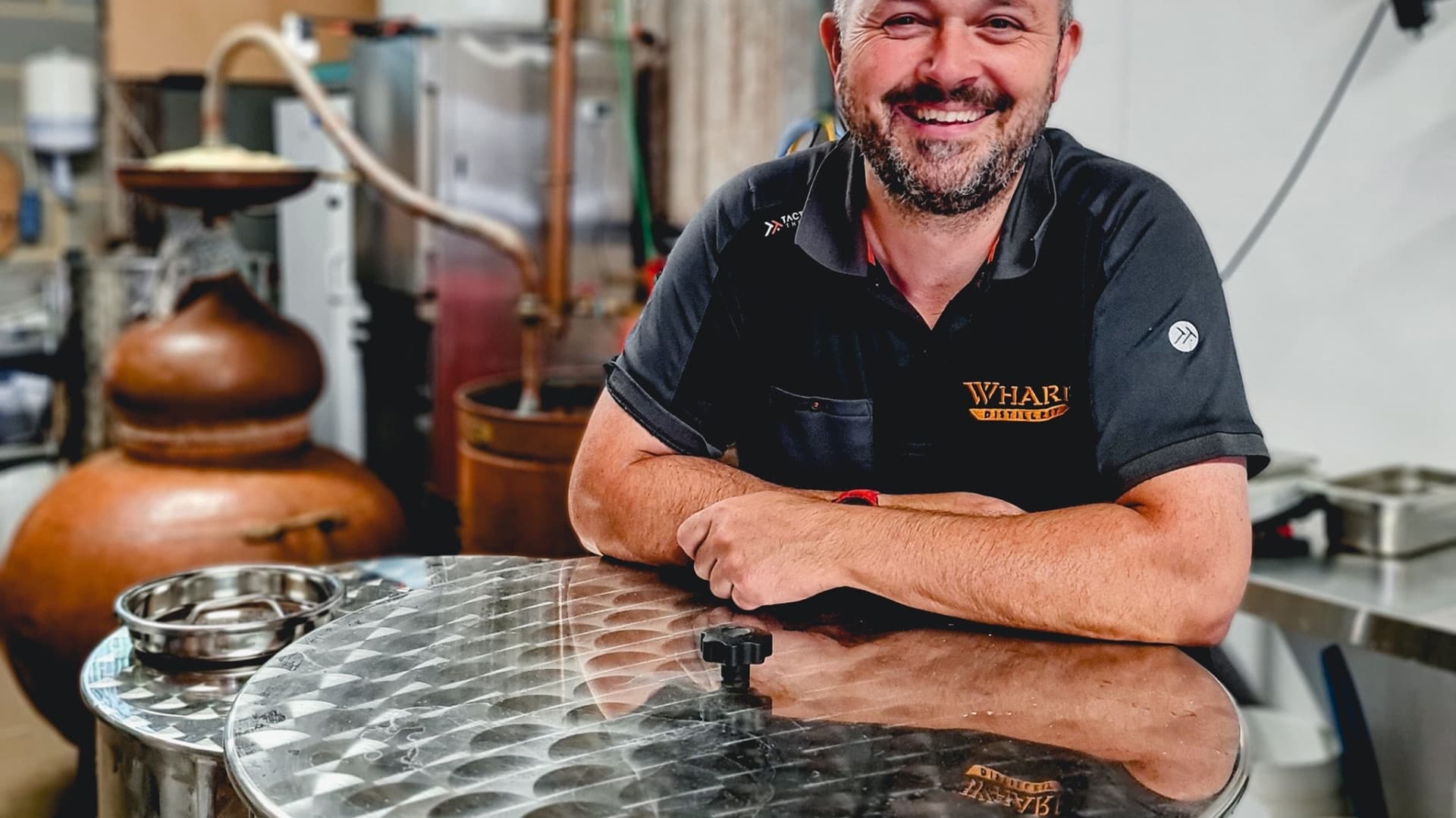 Distillery master beside copper stills in indoor whisky tasting