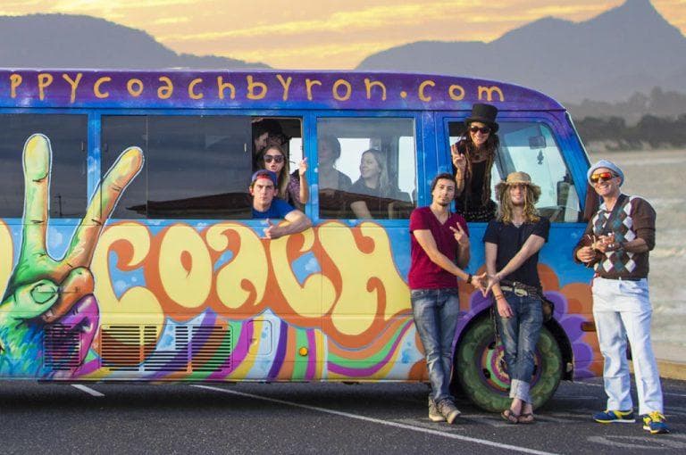 Group of travelers posing by colorful coach bus at scenic stop