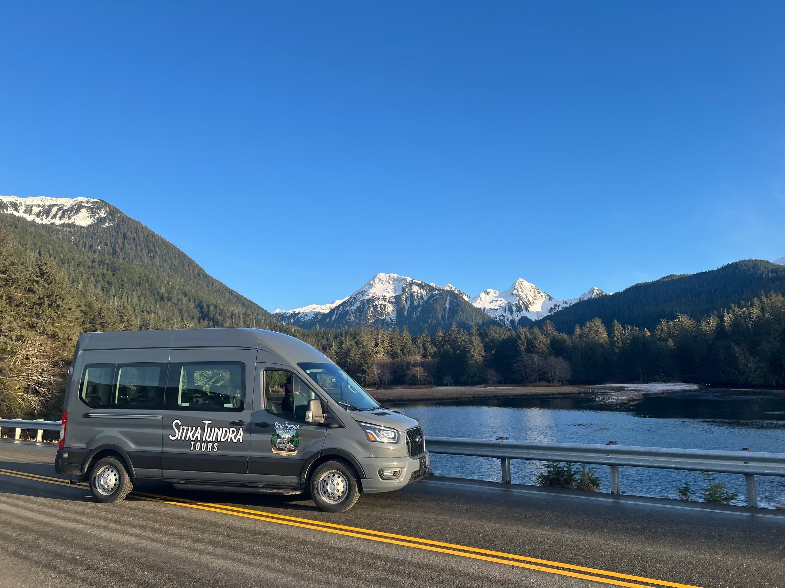 Scenic mountain lake drive with tour van on highway in Alaska