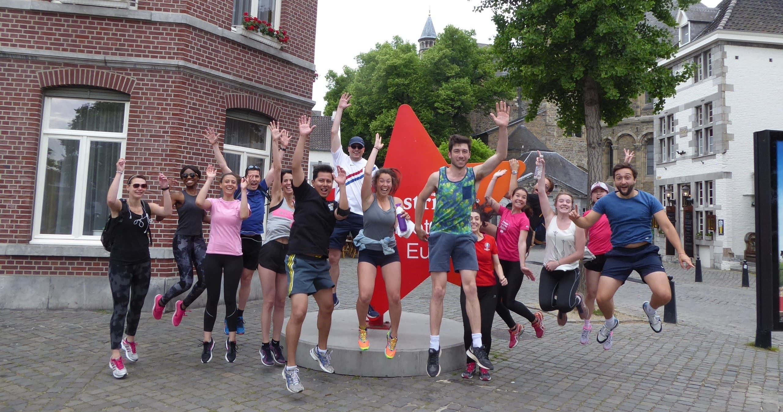 Group running tour participants jumping in Maastricht town square