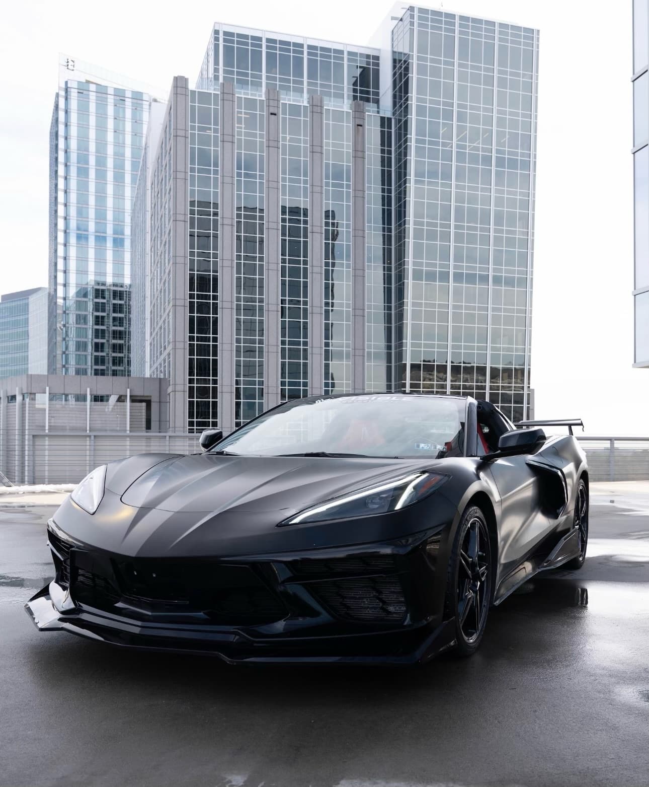 Black Corvette convertible on rooftop with city skyline for cruise