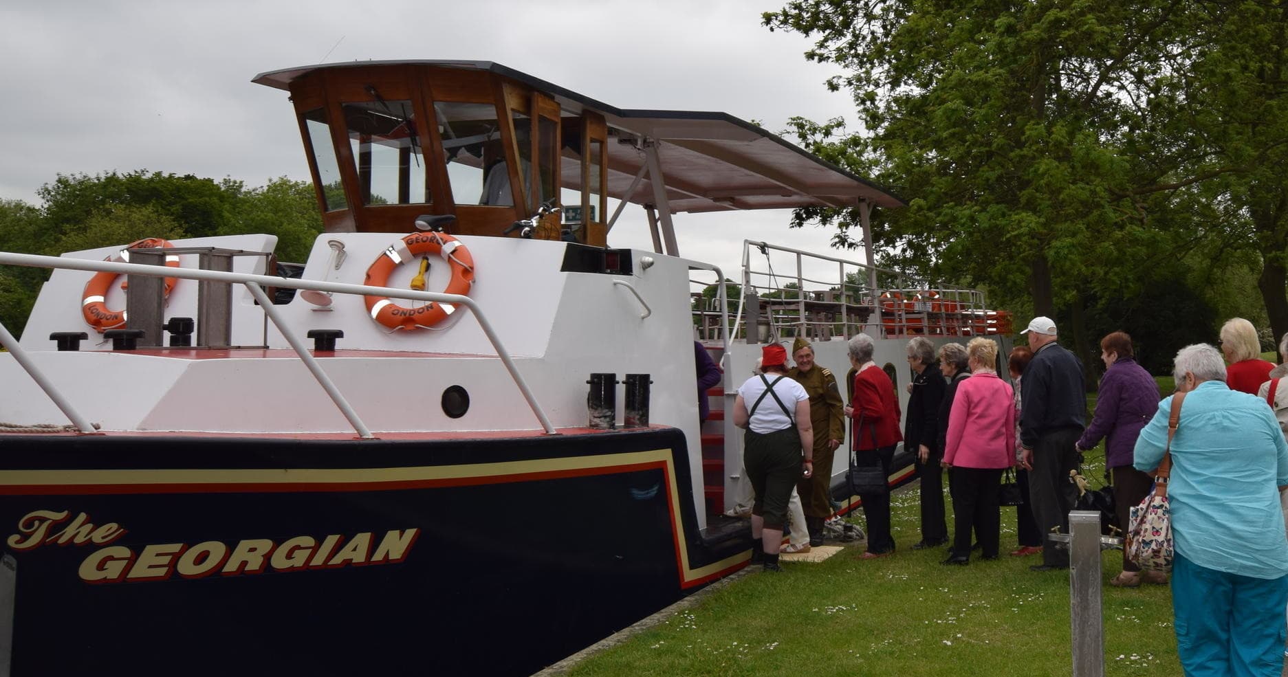 Passengers boarding river cruise boat on scenic riverside quay