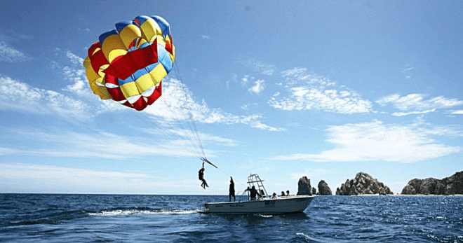 Parasailing over Cabo ocean with colorful chute and boat
