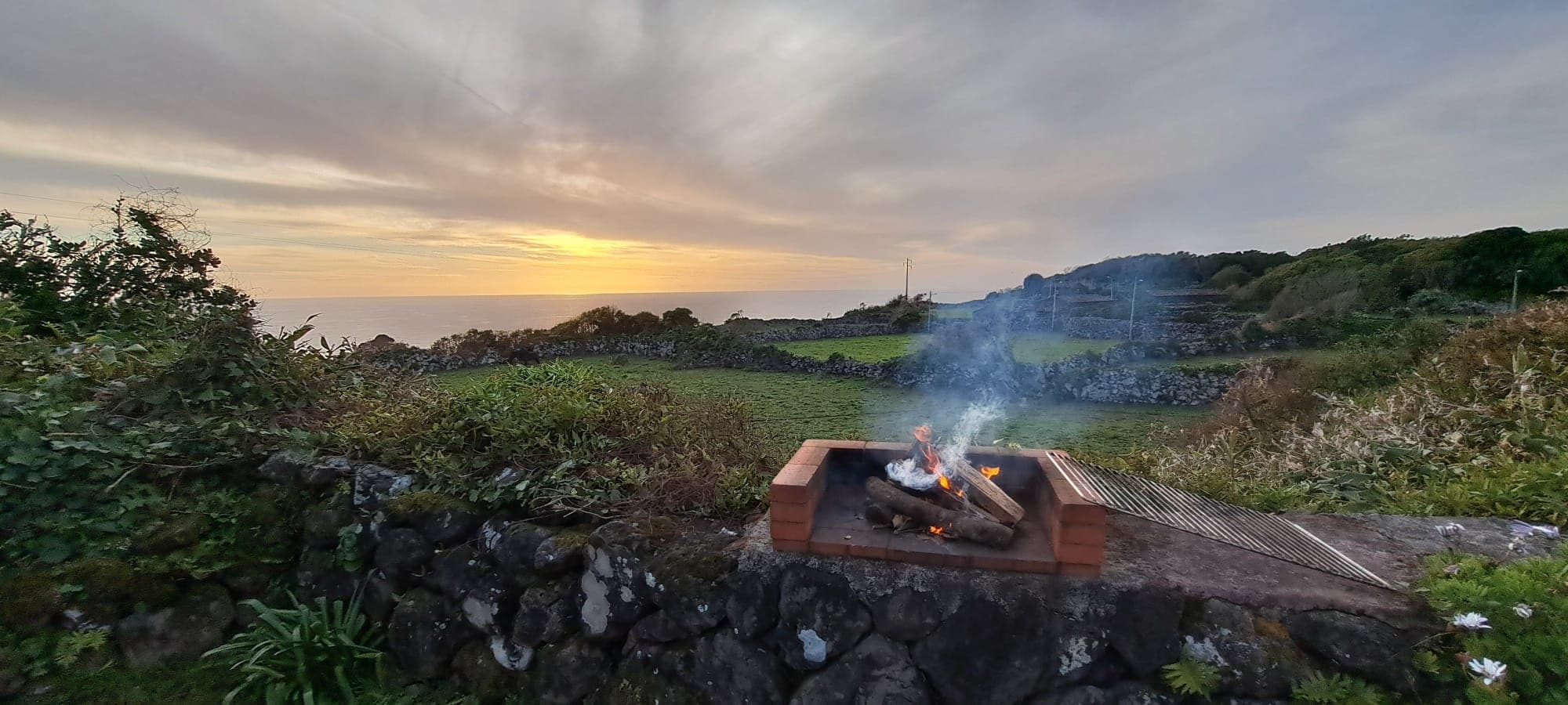 Coastal campsite with sunset campfire and campervan by the shore