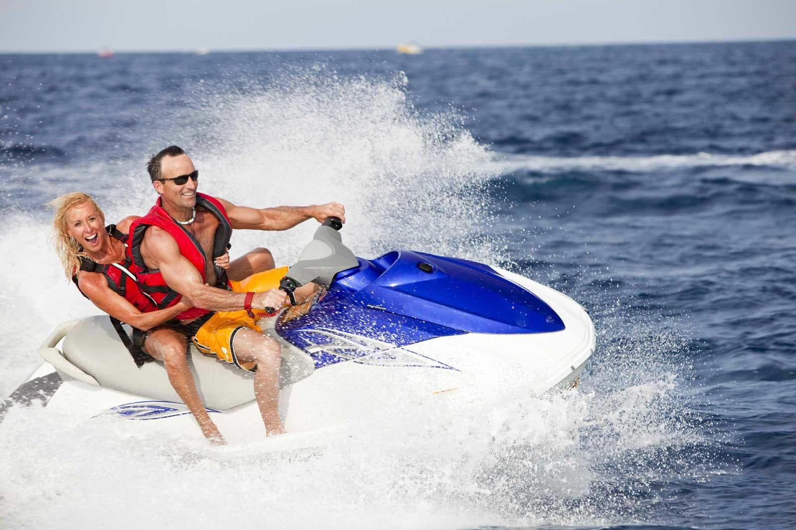 Couple riding jet ski on open ocean waves for water adventure
