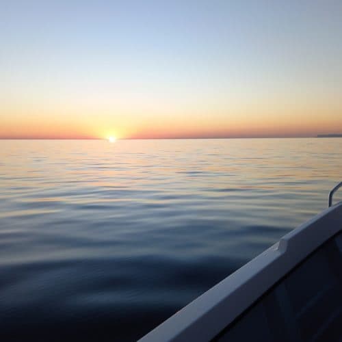 Sunset boat cruise over calm Atlantic waters off Sesimbra