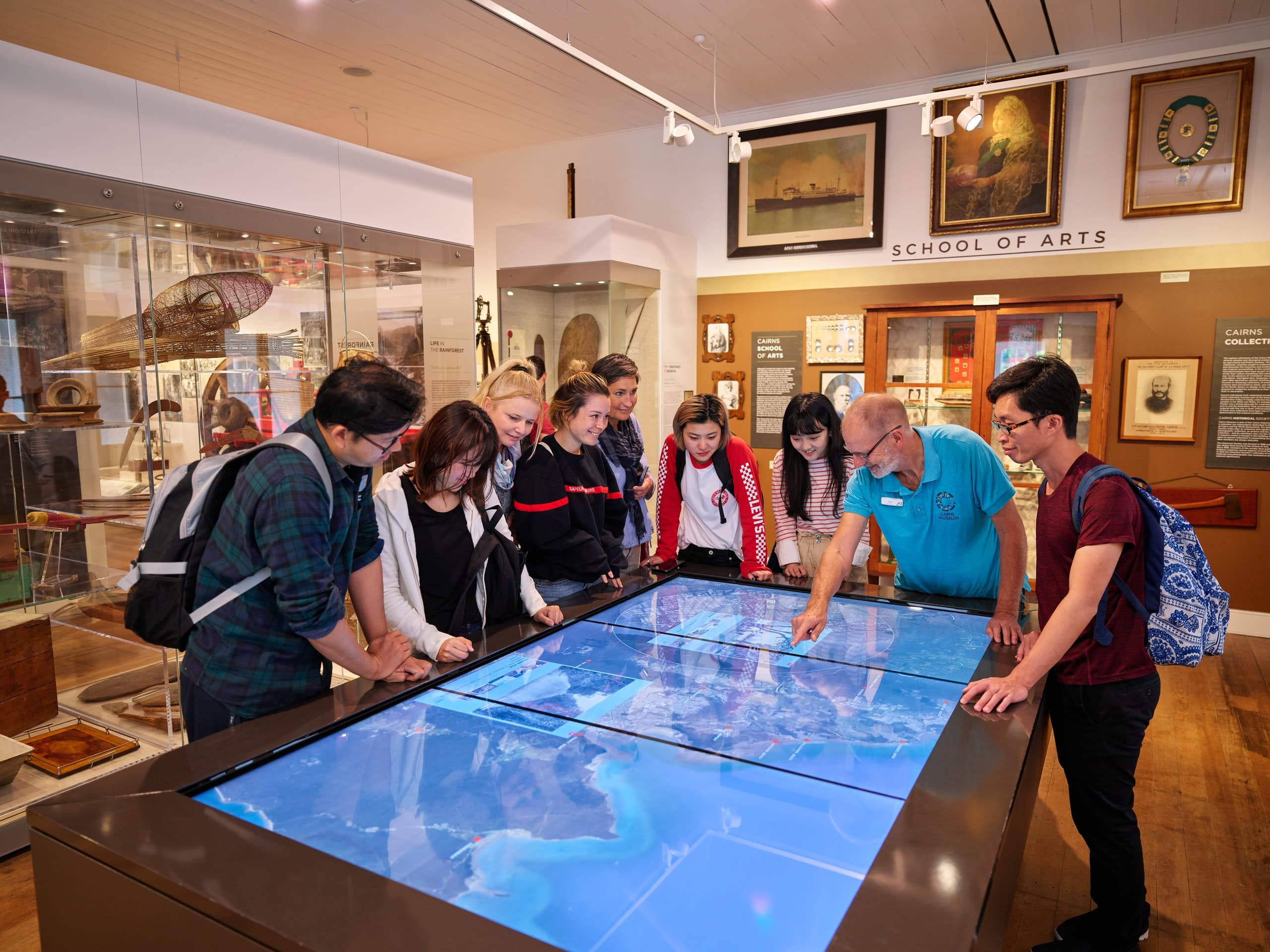 Visitors exploring interactive touch table exhibit inside museum gallery