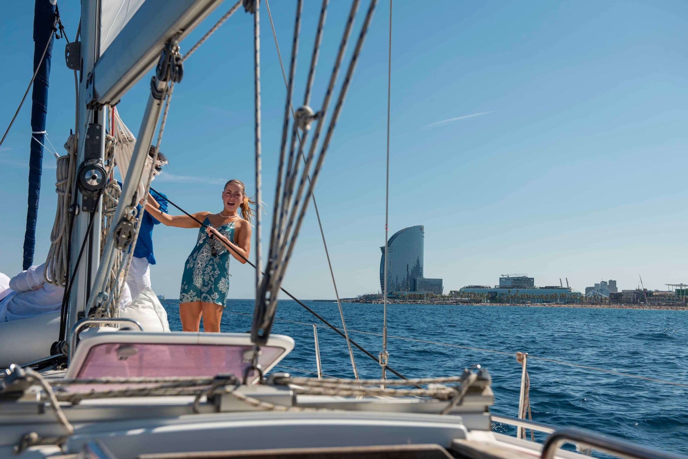 Woman on yacht bow sailing near Barcelona waterfront skyline