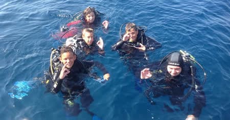 Group of scuba divers giving OK sign at sea during excursion