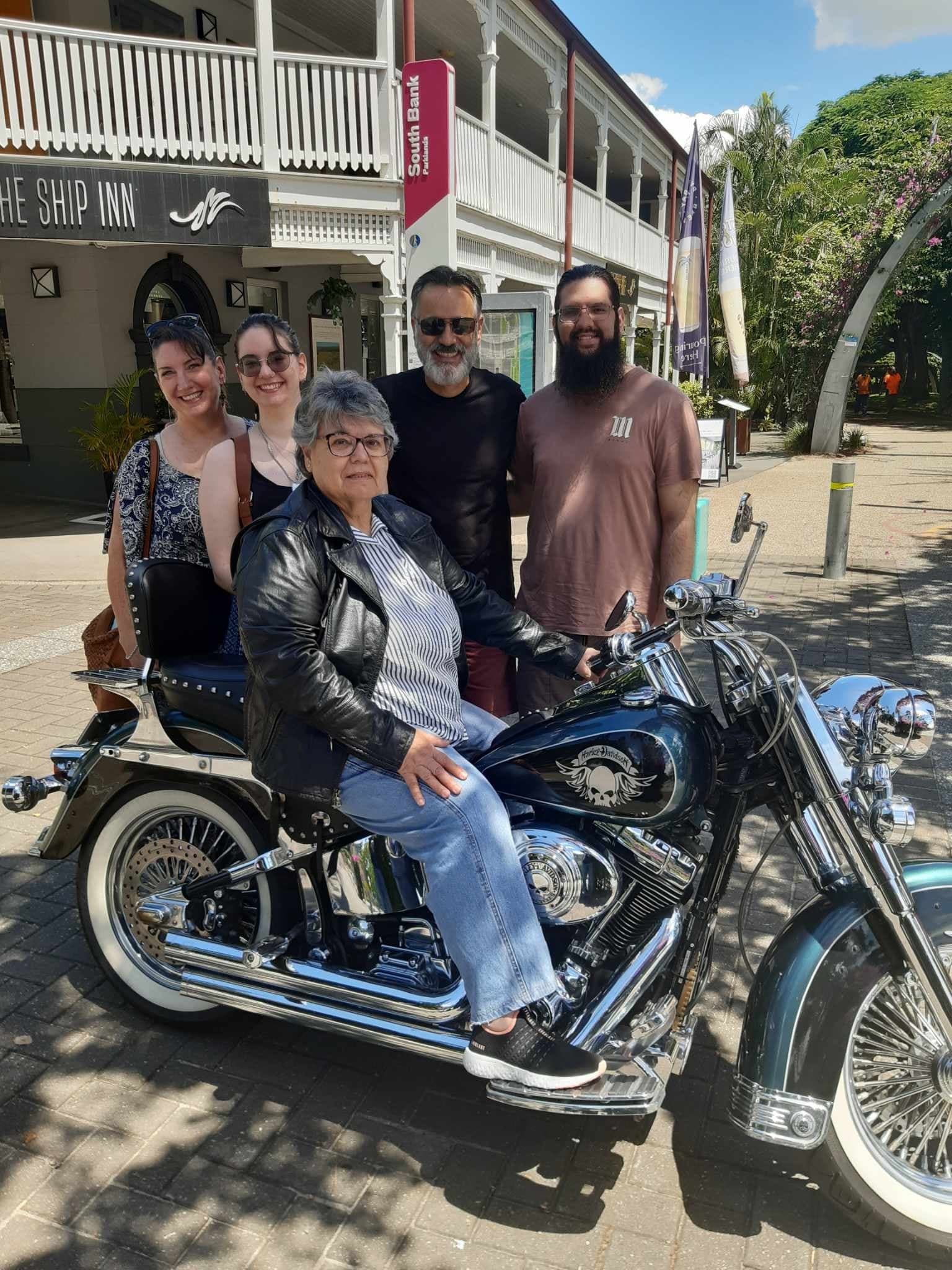 Passenger seated on parked Harley motorcycle in coastal Queensland town