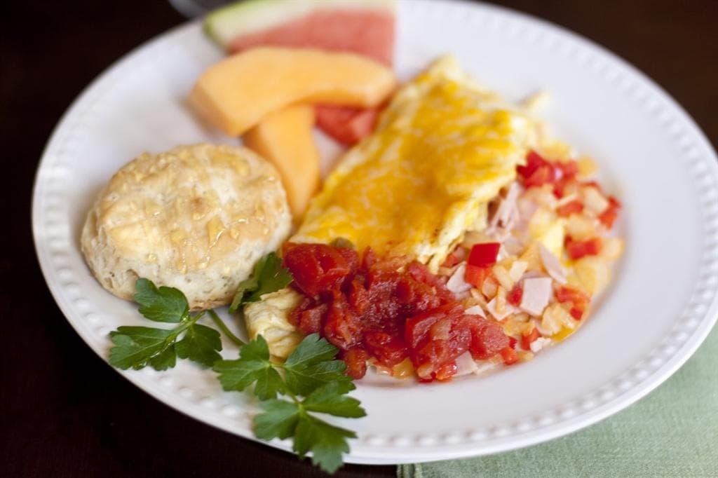 Hearty breakfast plate with omelet, biscuit, and fruit