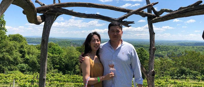 Couple posing under wooden pergola with vineyard valley view