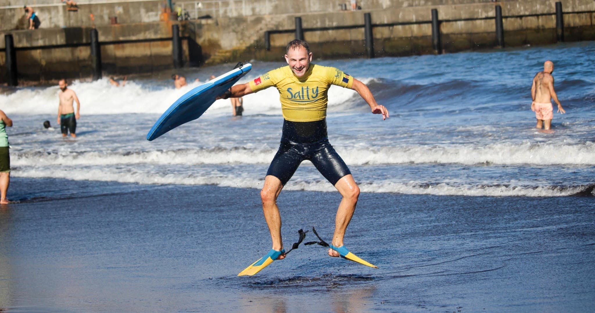 Surfer with fins on sandy beach preparing to enter surf
