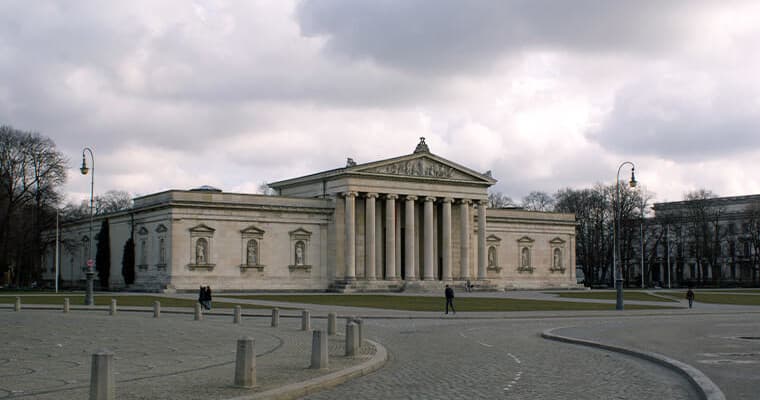 Visitors walking by neoclassical museum façade in city park