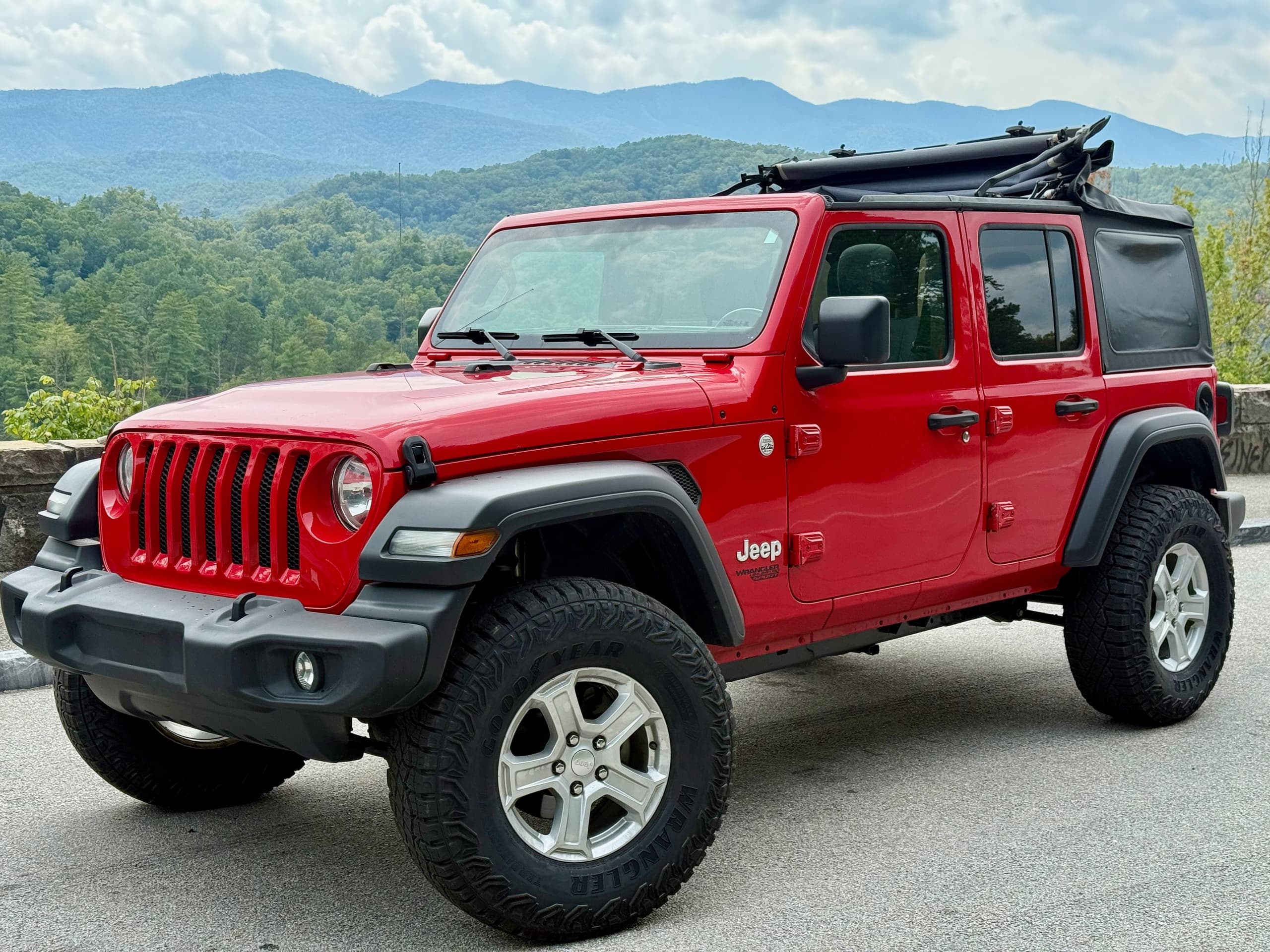 Red Jeep Wrangler overlooking mountain vista for scenic drive