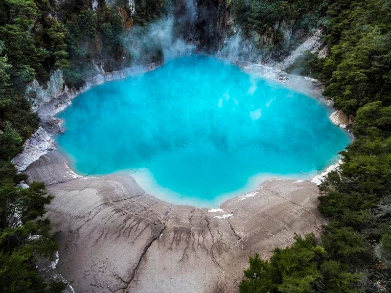 Aerial turquoise crater lake surrounded by forest, Rotorua area