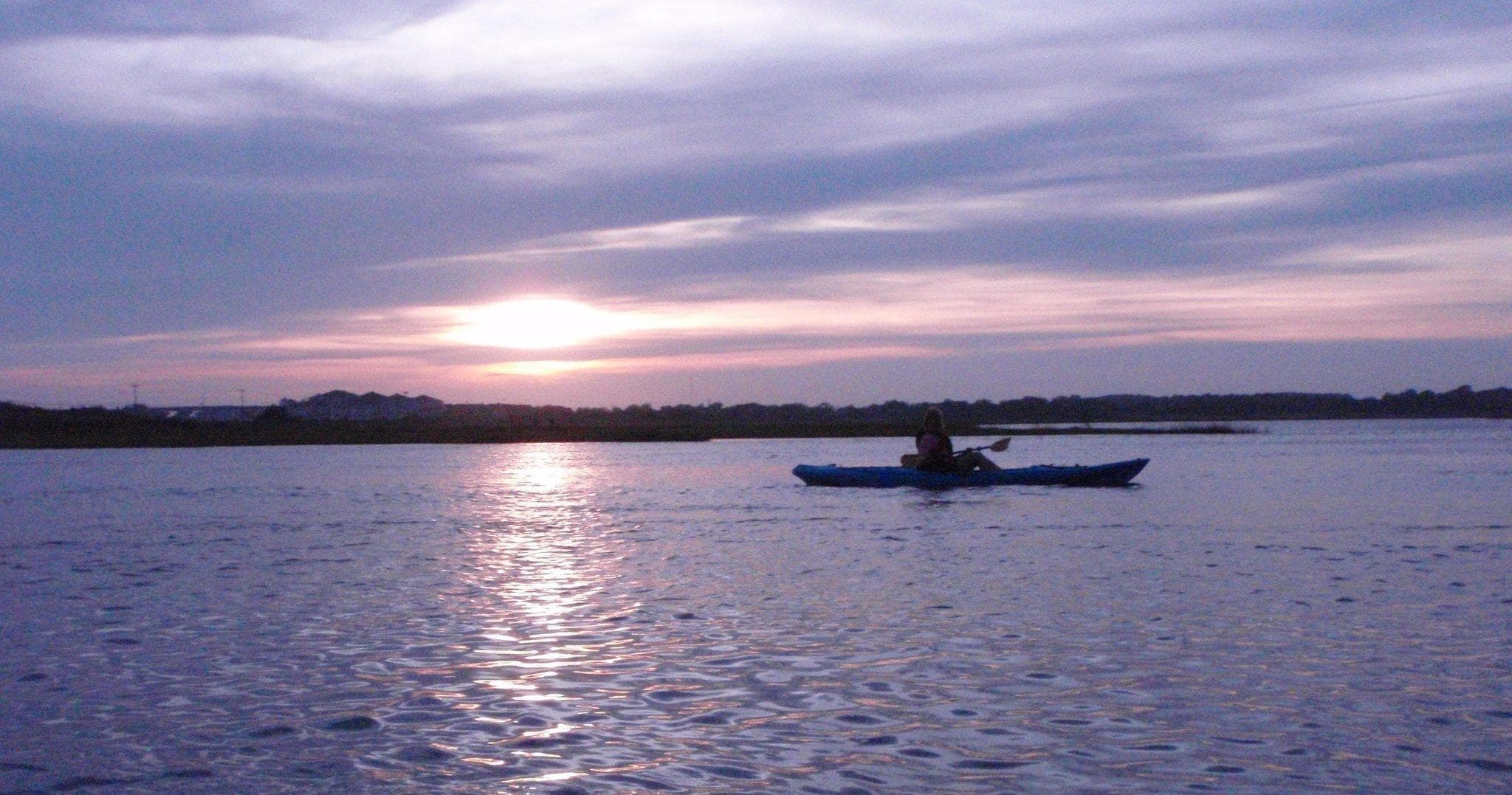 Solitary kayak on purple twilight over peaceful bay