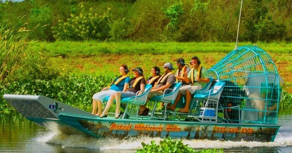 Airboat tour with passengers speeding through Florida wetlands