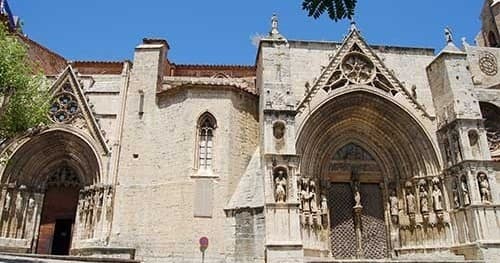 Visiting Gothic cathedral facade in sunlit historic European plaza