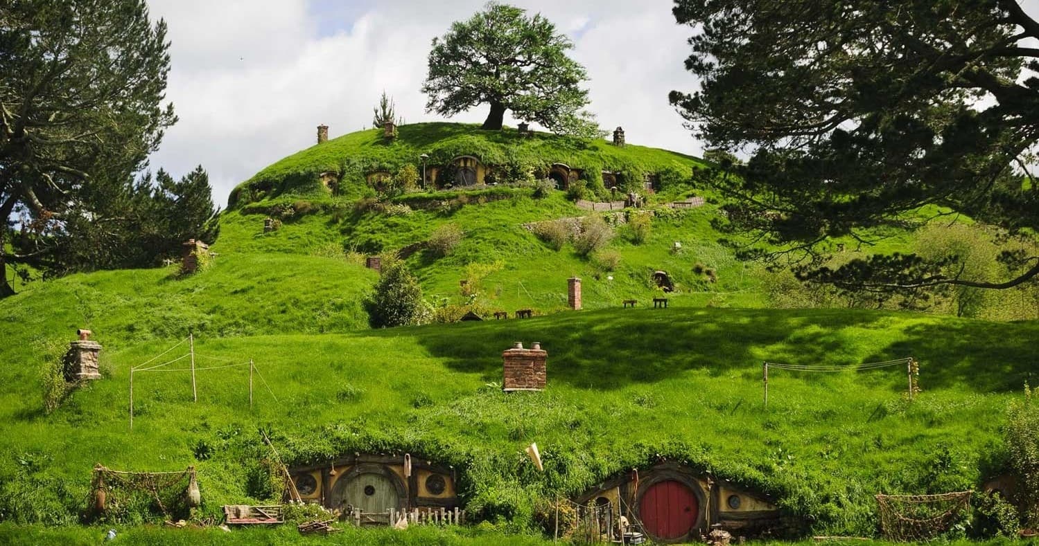 Green hillside hobbit-like village with walking trails and tours