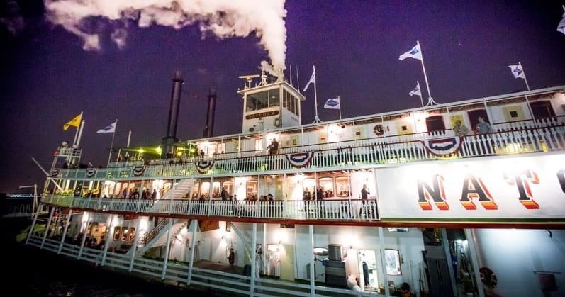Illuminated riverboat at night on Mississippi River, New Orleans skyline