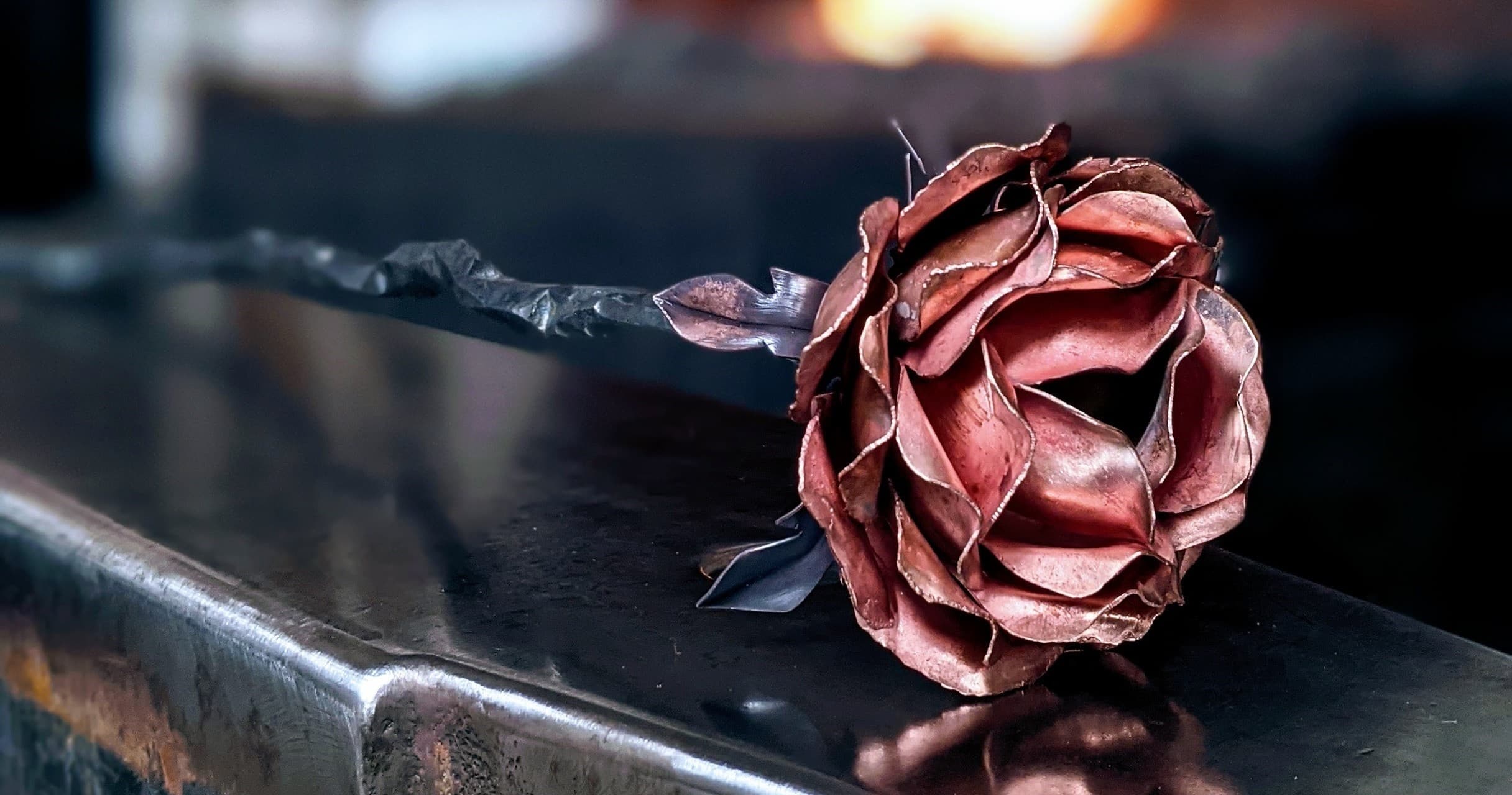 Forged steel rose resting on anvil in blacksmith workshop view