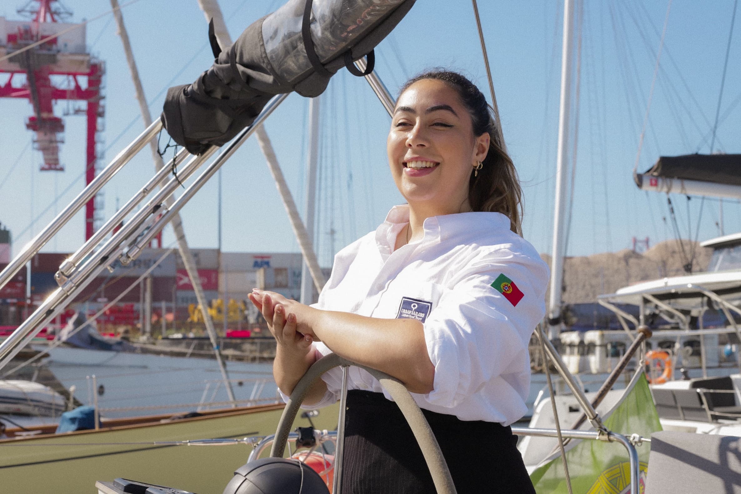 Woman steering sailboat in marina, sunny coastal sailing experience