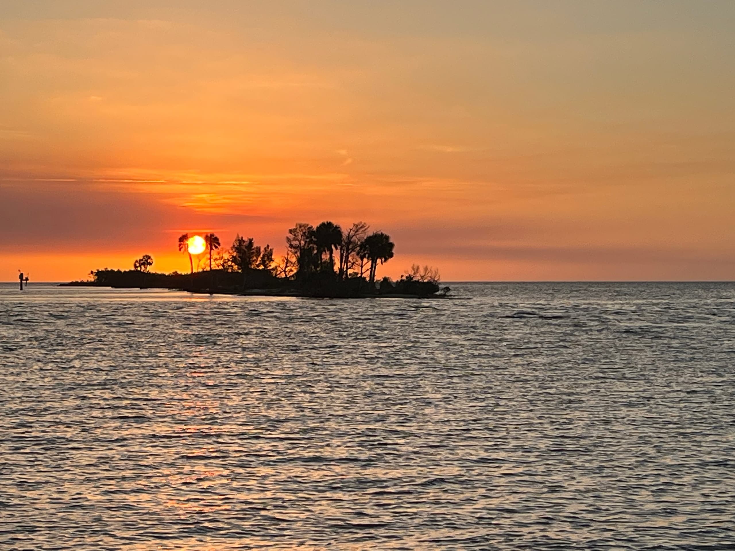 Golden sunset behind island skyline over tranquil coastal waters