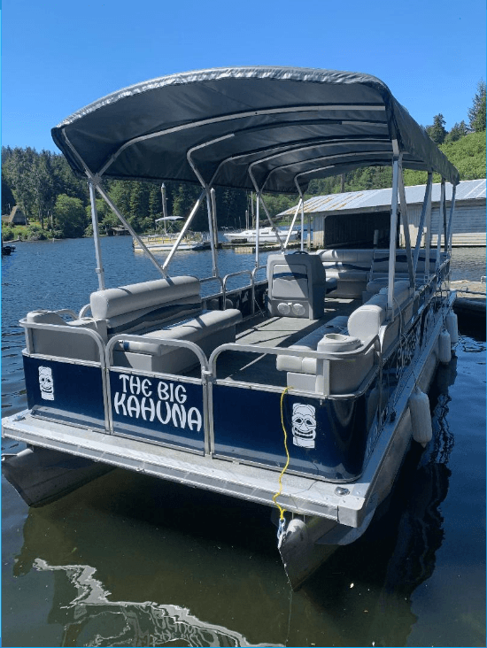 Pontoon boat stern with canopy docked on clear blue lake