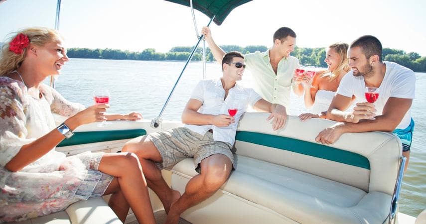 Group relaxing on pontoon boat sipping drinks, daytime lake outing