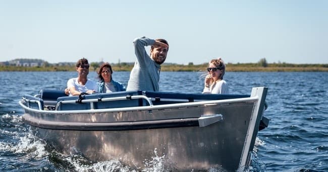 Small motorboat with friends cruising coastal lake waters at speed