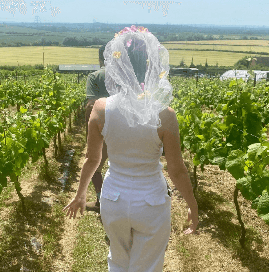 Person walking through vineyard rows wearing a floral veil event