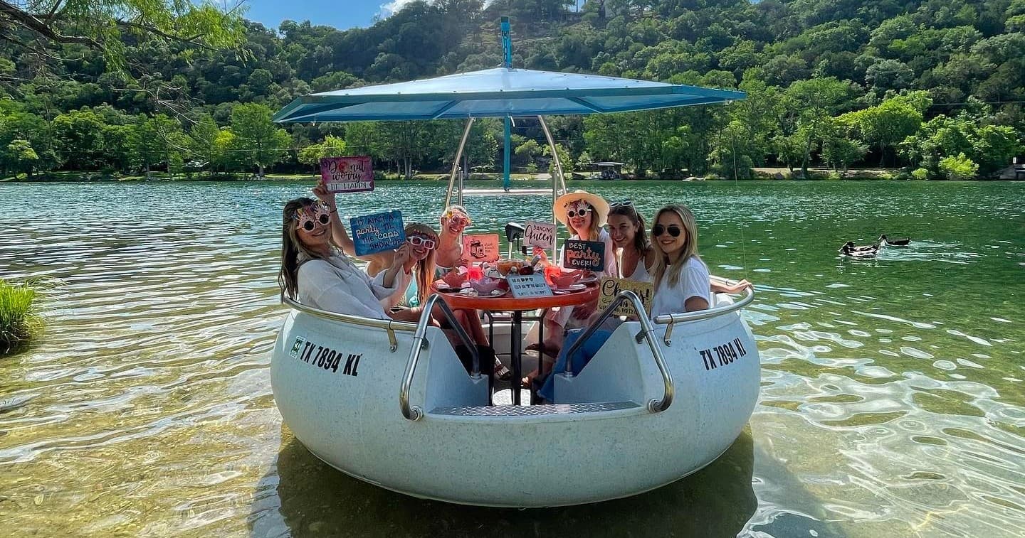 Group relaxing on round picnic boat on scenic lakeside cove