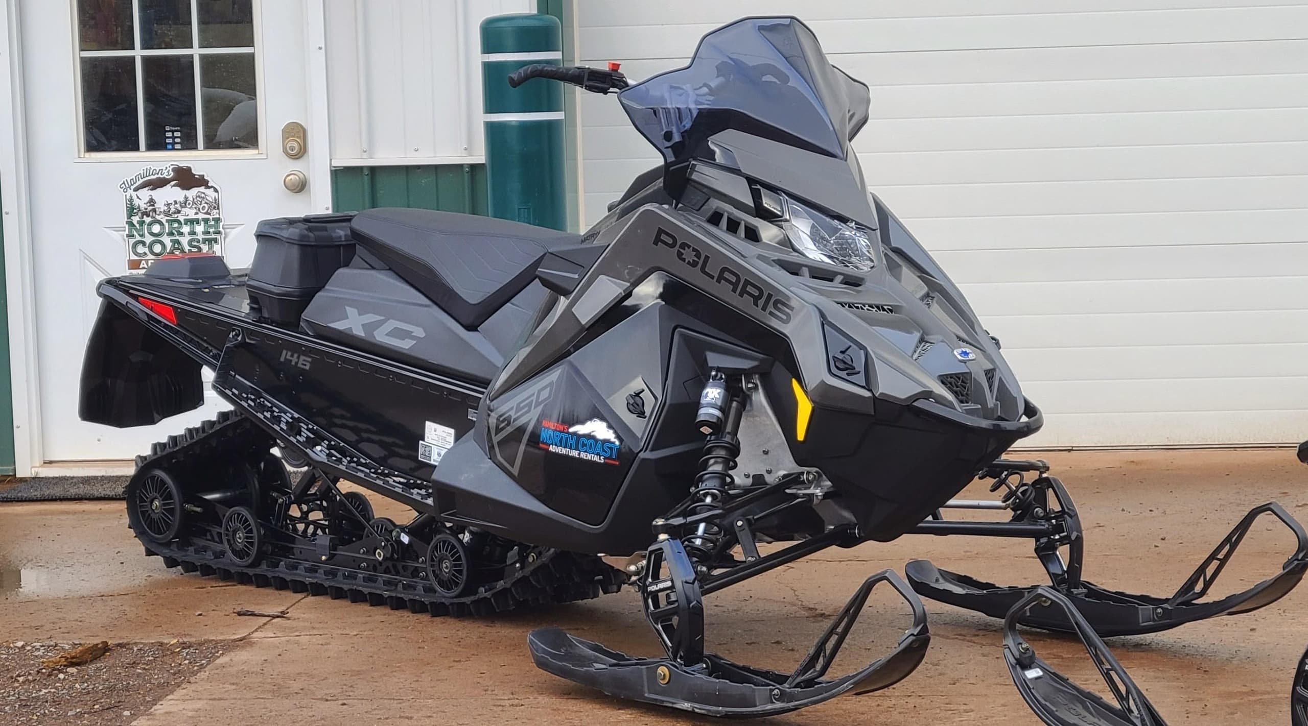 Snowmobile parked by lodge in winter, guided snowmobile excursion