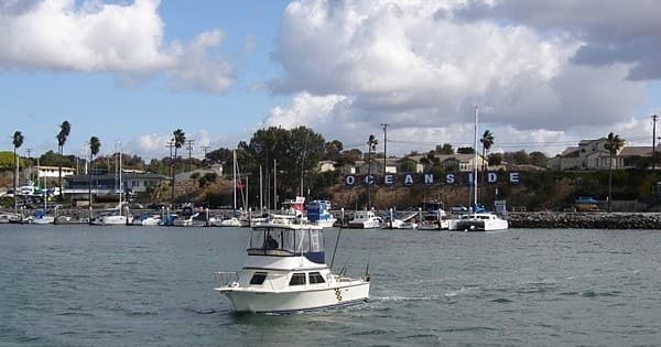 Charter fishing boat cruising near Oceanside marina under cloudy sky
